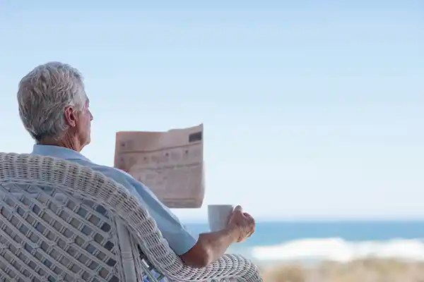 aposentado tomando cafe e lendo jornal na praia de itapema
