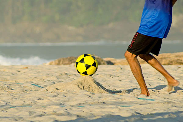 Pessoa chutando bola de futevôlei